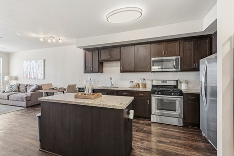 A modern kitchen with dark wood cabinets and stainless steel appliances.