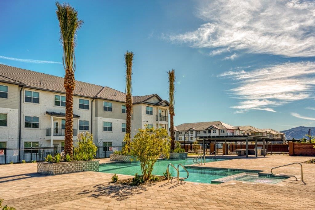 a swimming pool with palm trees in front of an apartment building