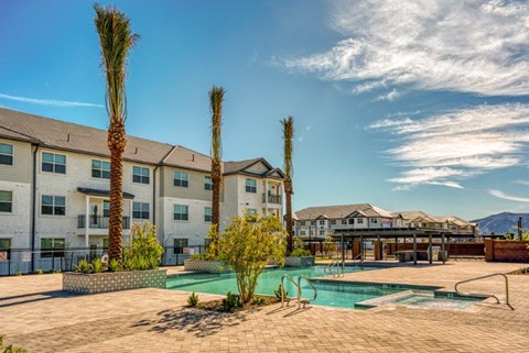 a swimming pool with palm trees in front of an apartment building