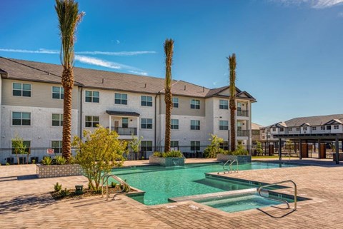 a swimming pool with palm trees in front of an apartment building