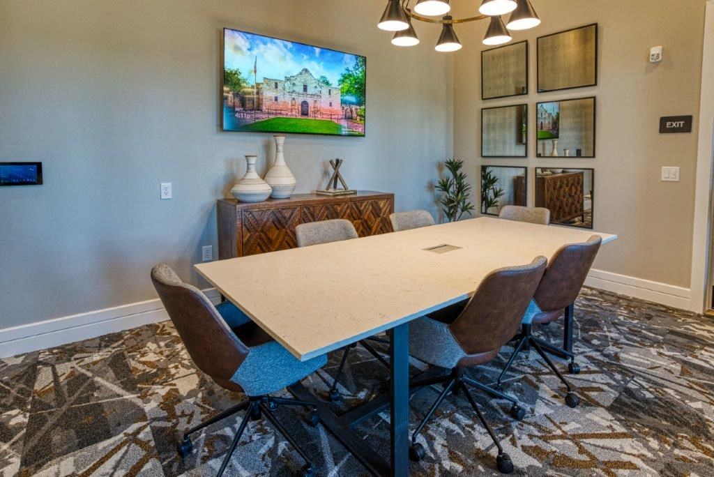a conference room with a table and chairs and a tv on the wall