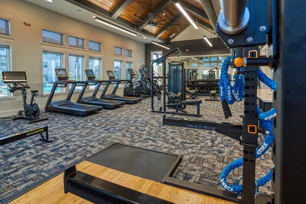 a gym with cardio equipment and a row of exercise machines