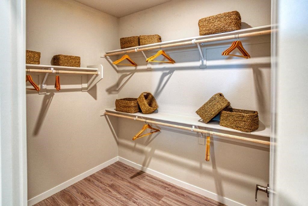 a walk in closet with baskets on shelves