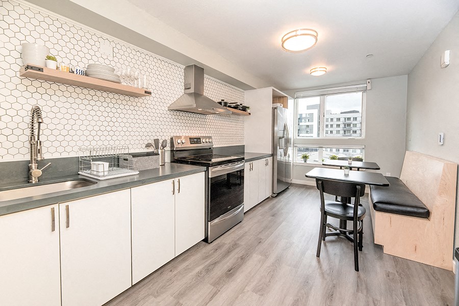 a kitchen with white cabinets and a black table and chairs