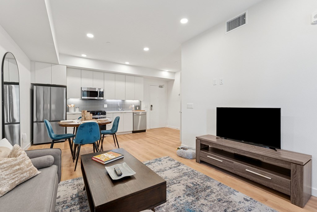 OnyxOnPark_SanDiego_CA_Model_1BR_ A modern living room with a grey sofa, a wooden coffee table, and a black television.