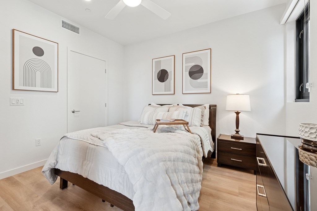 OnyxOnPark_SanDiego_CA_Model_1BR_ A bedroom with a large bed and two framed pictures on the wall.