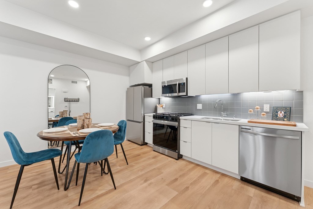 OnyxOnPark_SanDiego_CA_Model_1BR_ A modern kitchen with a dining table and chairs.