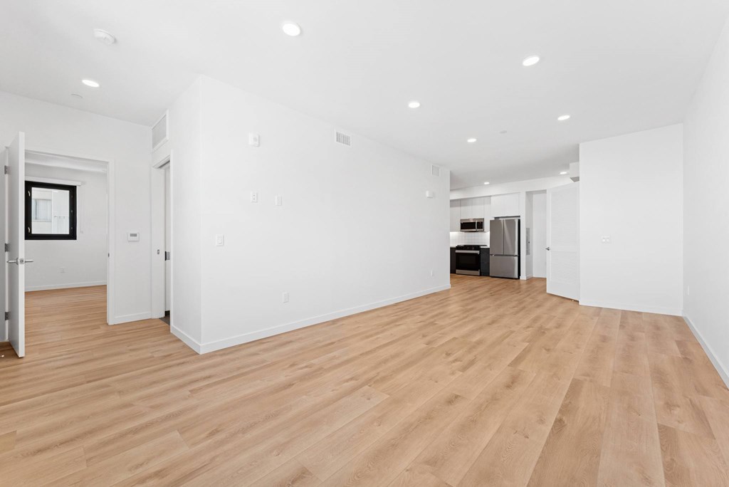 OnyxOnPark_SanDiego_CA_Vacant_2BR_ A large empty room with wooden floors and white walls.