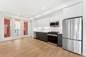 A modern kitchen with stainless steel appliances and wooden flooring.