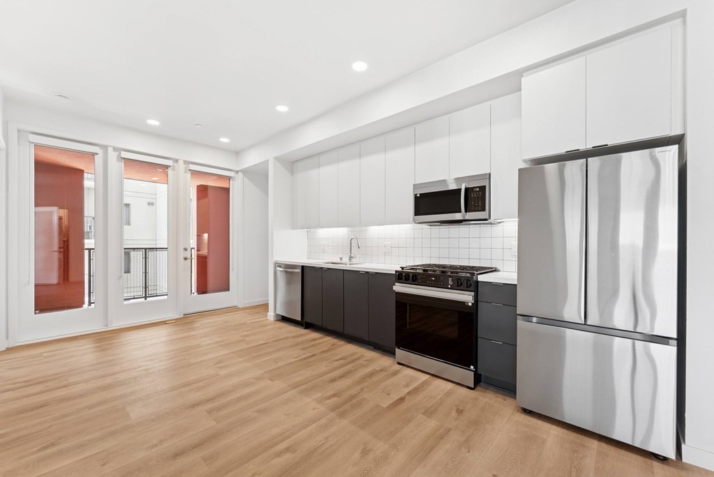 OnyxOnPark_SanDiego_CA_Vacant_2BR_ A modern kitchen with stainless steel appliances and wooden flooring.