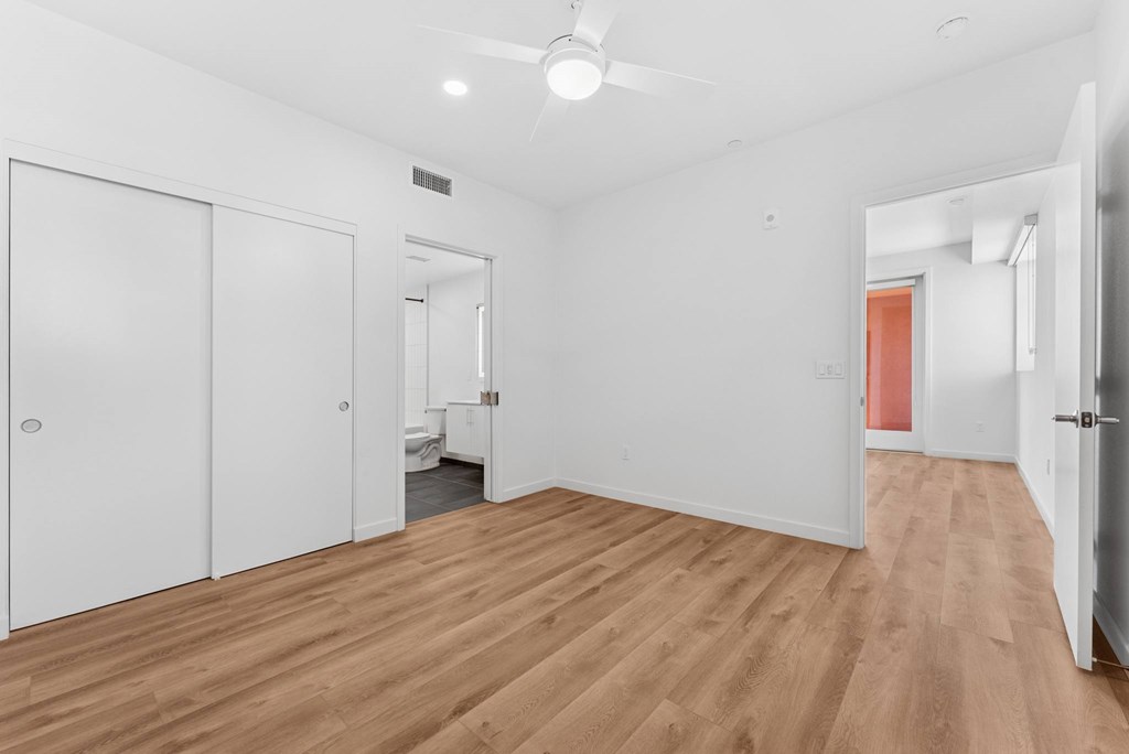 OnyxOnPark_SanDiego_CA_Vacant_2BR_B1_A room with white walls and wooden flooring with a ceiling fan.