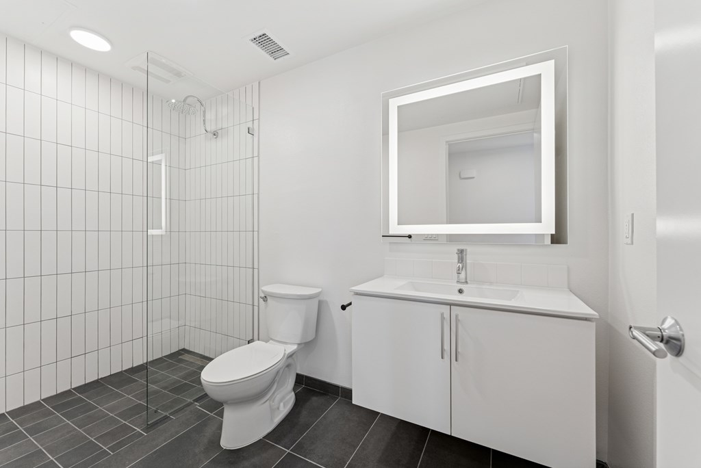 OnyxOnPark_SanDiego_CA_Vacant_2BR_B1_A white bathroom with a toilet, sink, and mirror.