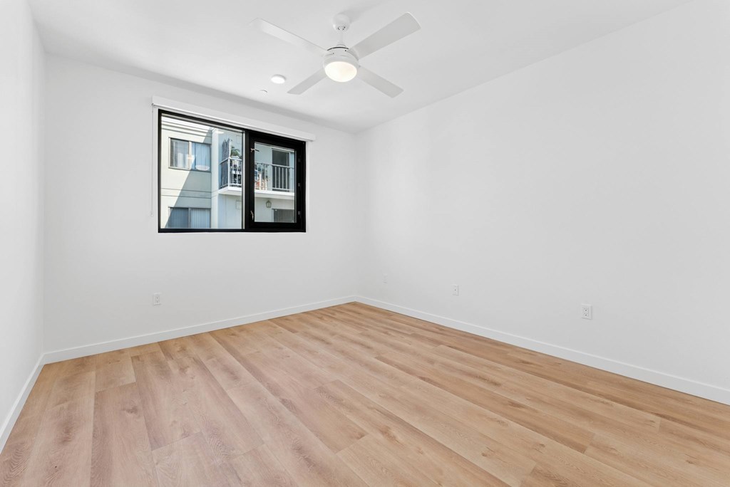OnyxOnPark_SanDiego_CA_Vacant_Penthouse_A_A room with a ceiling fan and a window showing a building outside.