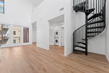 A black spiral staircase in a white room with wooden flooring.