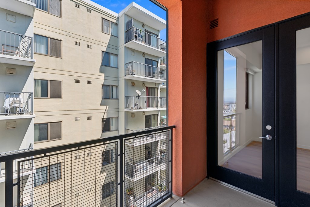 OnyxOnPark_SanDiego_CA_Vacant_Penthouse_A_A balcony with a black railing and a view of a building with orange and beige walls.