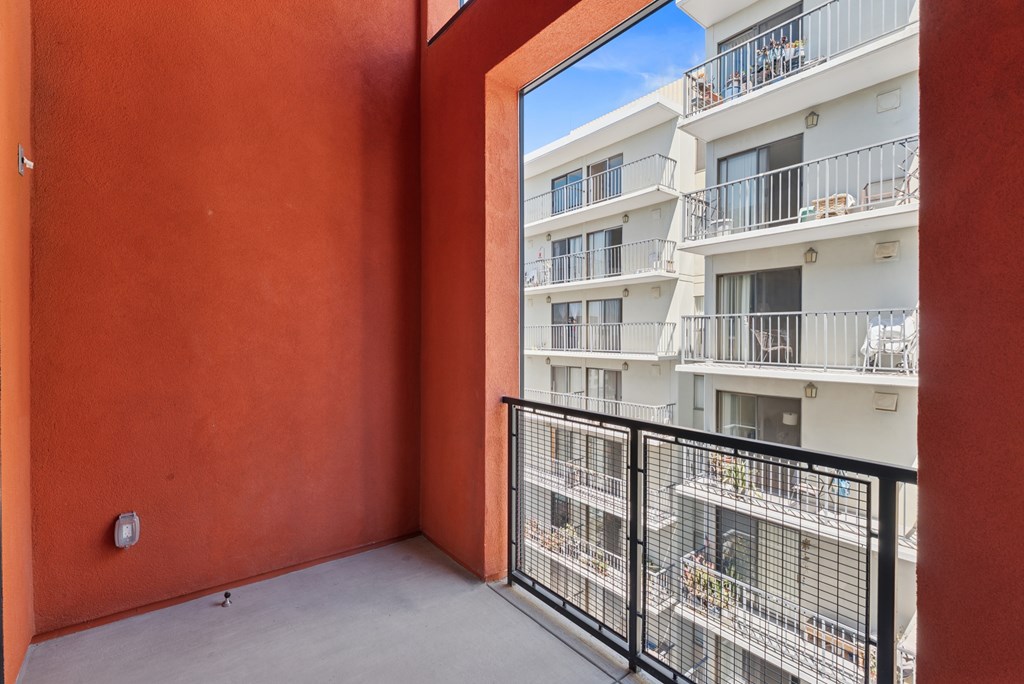 OnyxOnPark_SanDiego_CA_Vacant_Penthouse_A_A balcony with a black railing and a red wall.