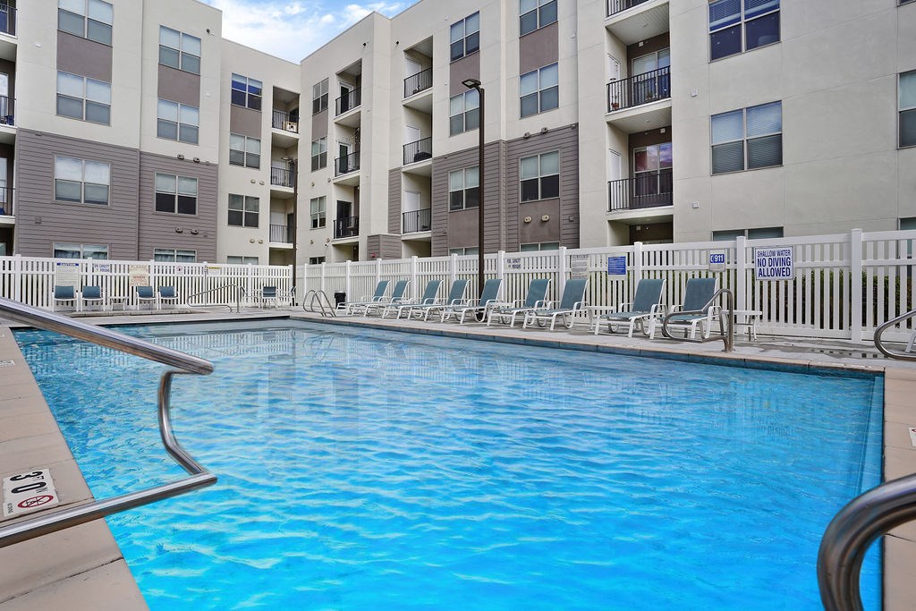 Alvera at the Meadows  swimming pool surrounded by a white fence and chairs.