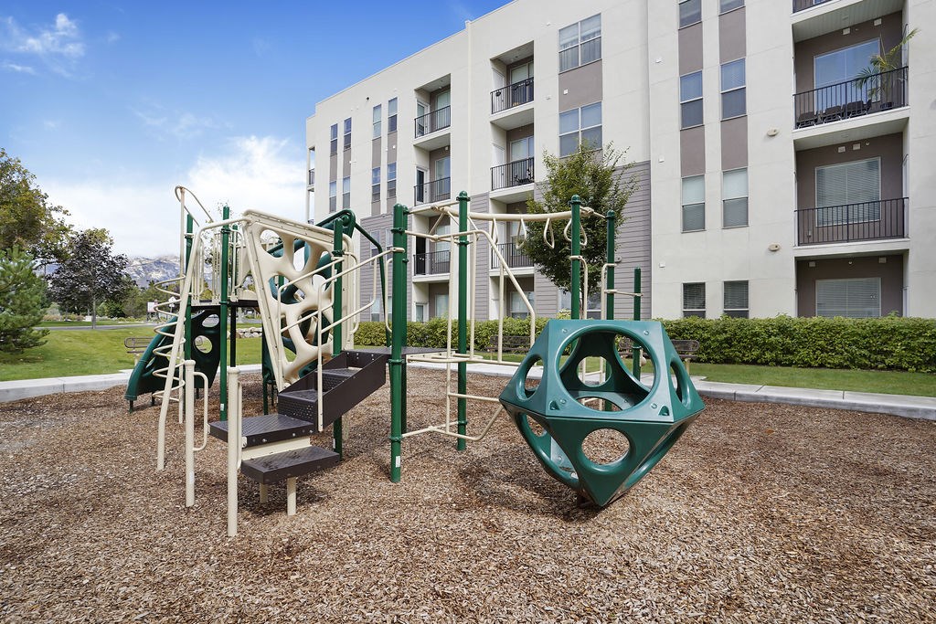 Alvera at the Meadows playground with a green slide and a climbing frame.