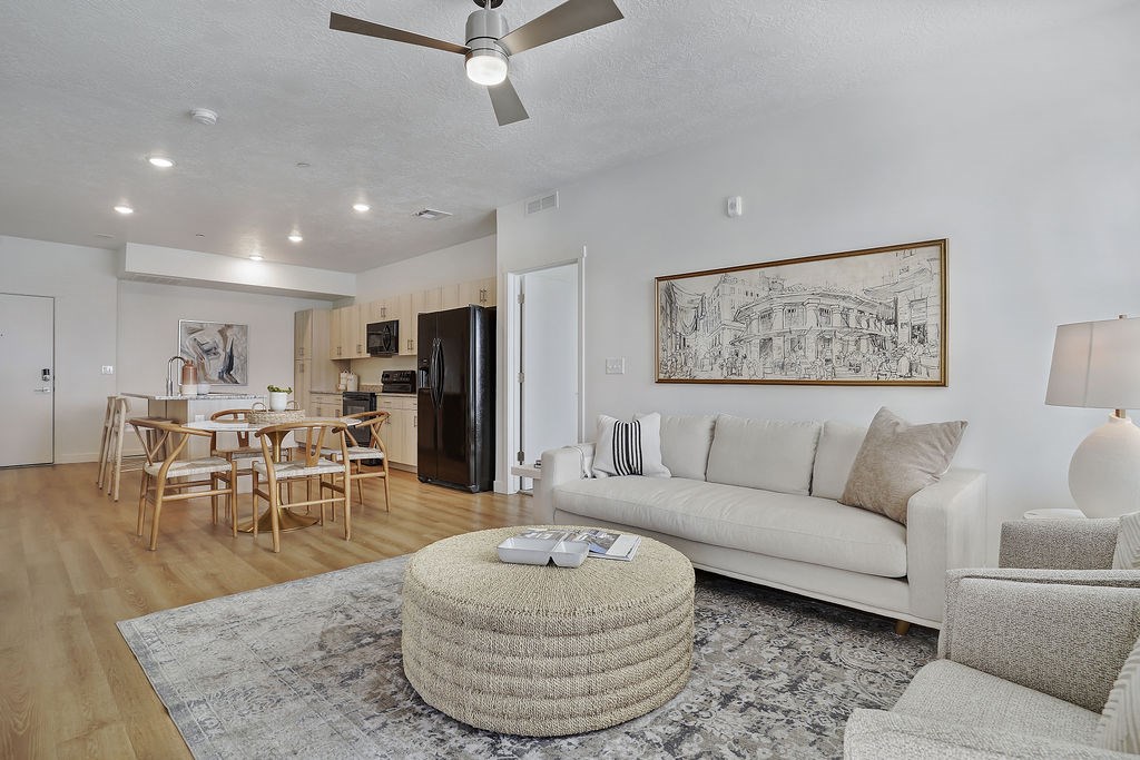 Alvera at the Meadows living room with a white couch, a round wicker coffee table, and a ceiling fan.