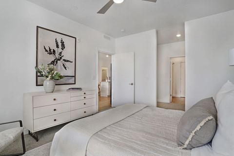 Alvera at the Meadows bedroom with a large bed, a dresser with a vase of flowers, and a framed picture on the wall.