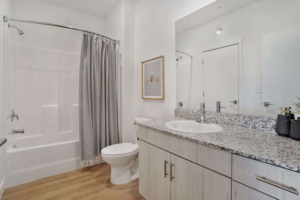 Alvera at the Meadows  bathroom with a white toilet, sink, and shower.