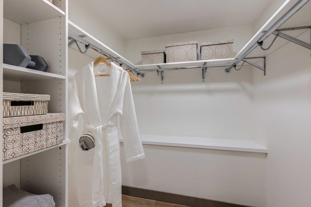 a walk in closet with a white robe and shelves