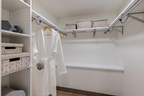 a walk in closet with a white robe and shelves
