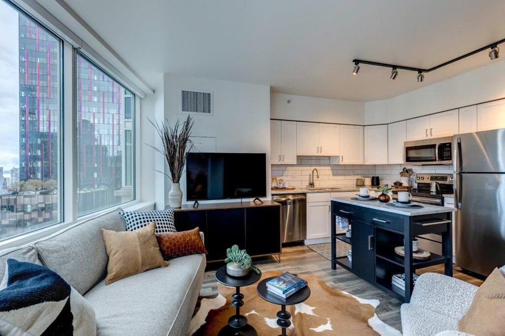 a living room with a couch and a kitchen with a large window