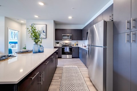 A modern kitchen with a stainless steel refrigerator and a striped rug on the floor.