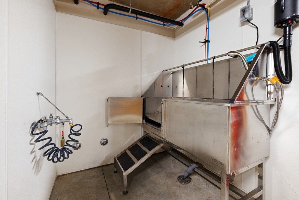 A large industrial machine with a metal frame and a white tank is in a room with a concrete floor.