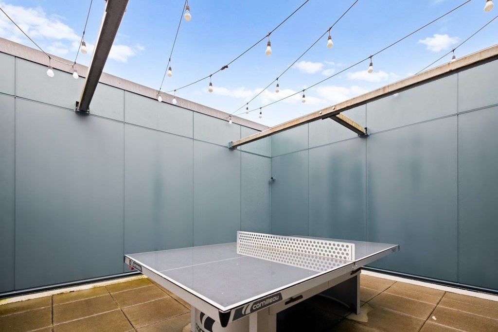 A ping pong table is in the middle of a room with a blue wall.