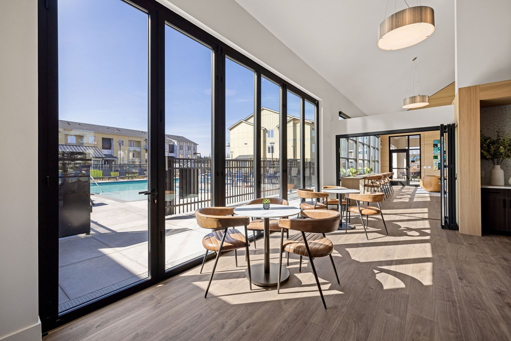 A modern dining area with a view of a pool and buildings outside.