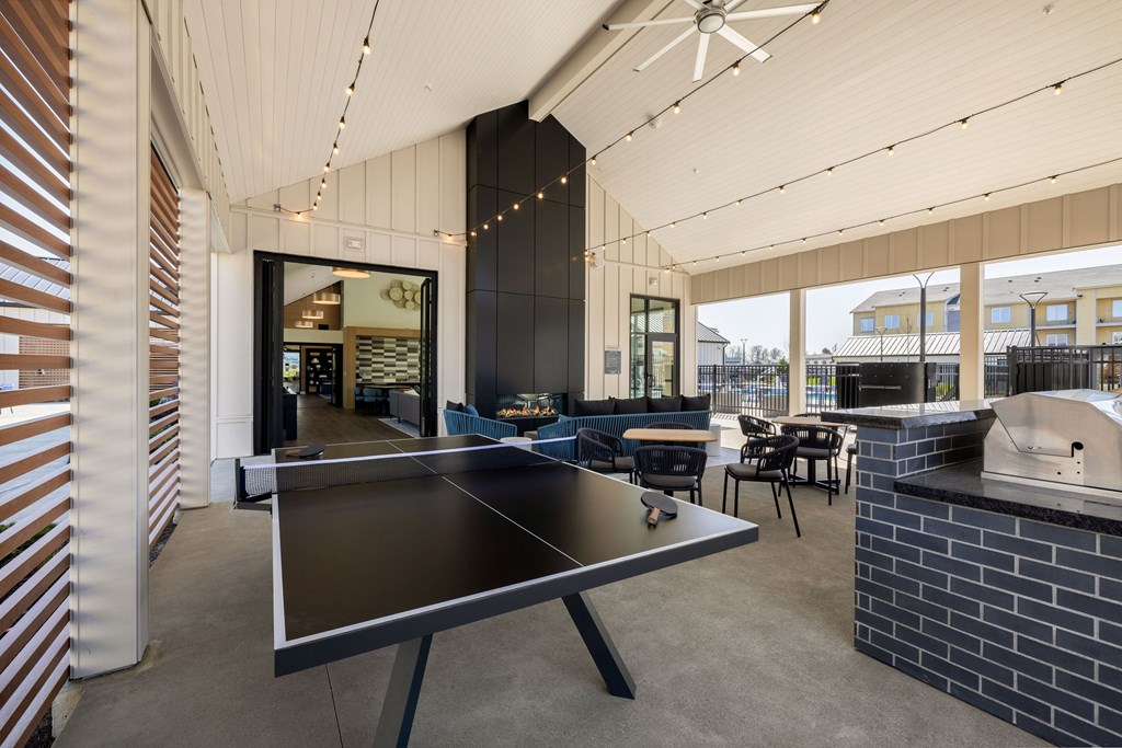 A ping pong table is in the middle of a room with a bar and a dining area.