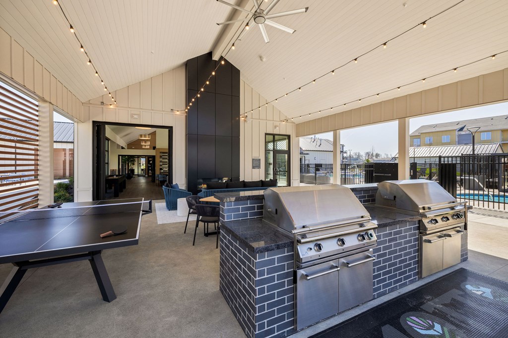 A patio with a table, chairs and a grill.