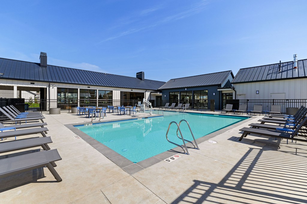 A large outdoor swimming pool with sun loungers and a building in the background.