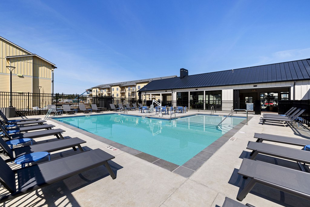 A pool with sun loungers and a building in the background.