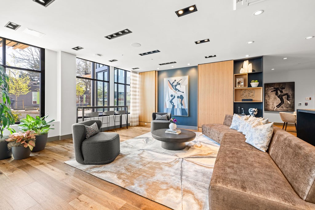 A living room with a brown couch, a grey armchair, and a round coffee table.