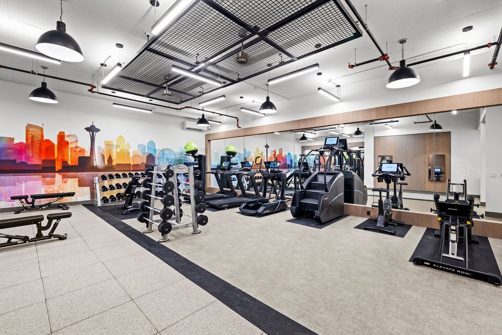 A gym with a variety of equipment including treadmills, weights, and exercise machines.