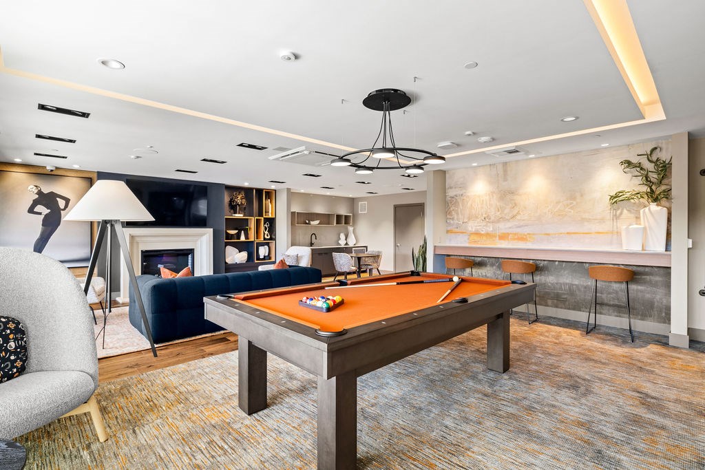 A billiard table is in the middle of a room with a blue couch and a fireplace.