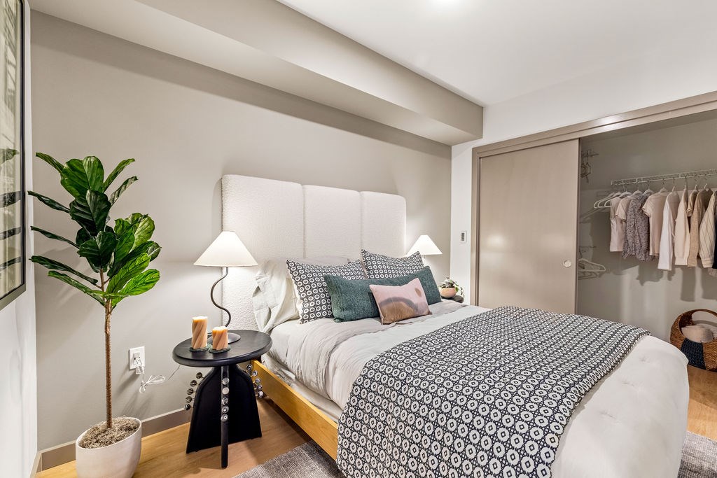 A bedroom with a large bed and a potted plant.
