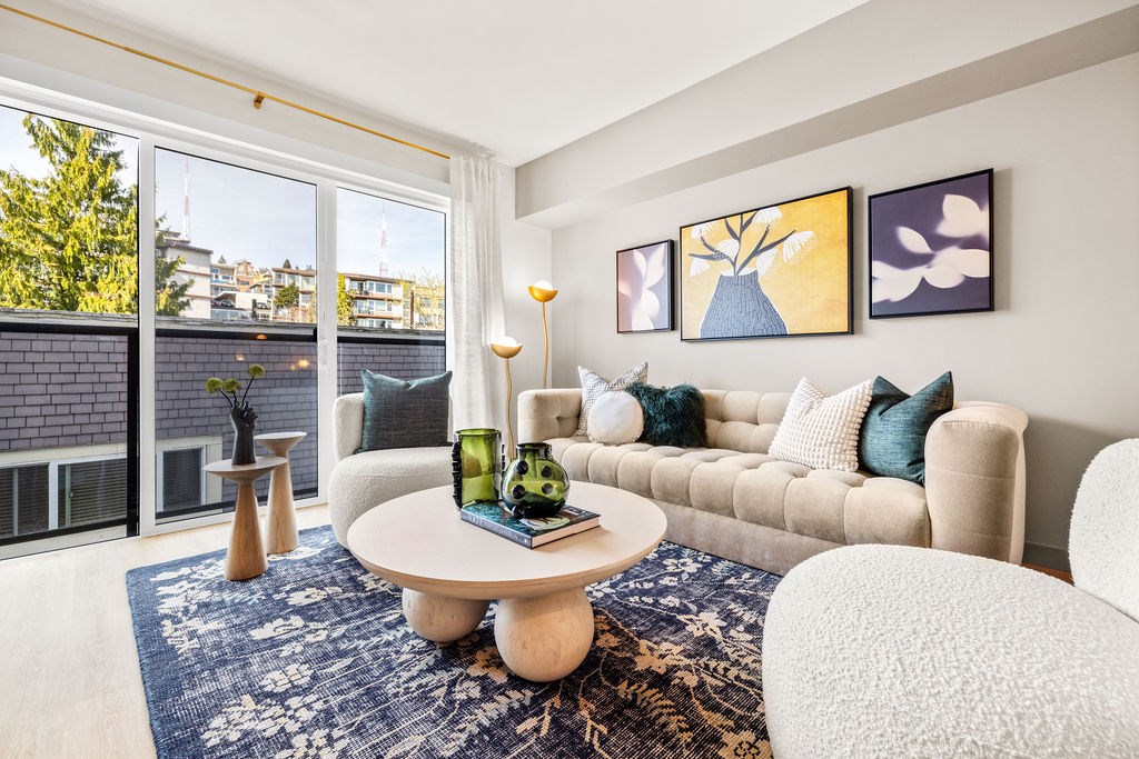A living room with a white couch, a round table, and a blue rug.