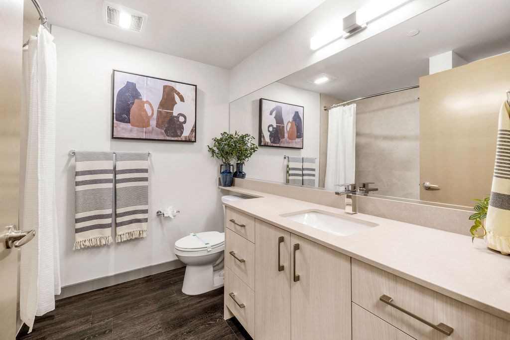 A bathroom with a toilet, sink, and mirror.