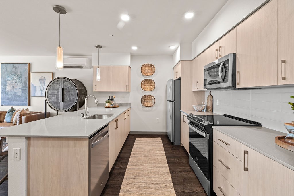 A modern kitchen with a white countertop and stainless steel appliances.