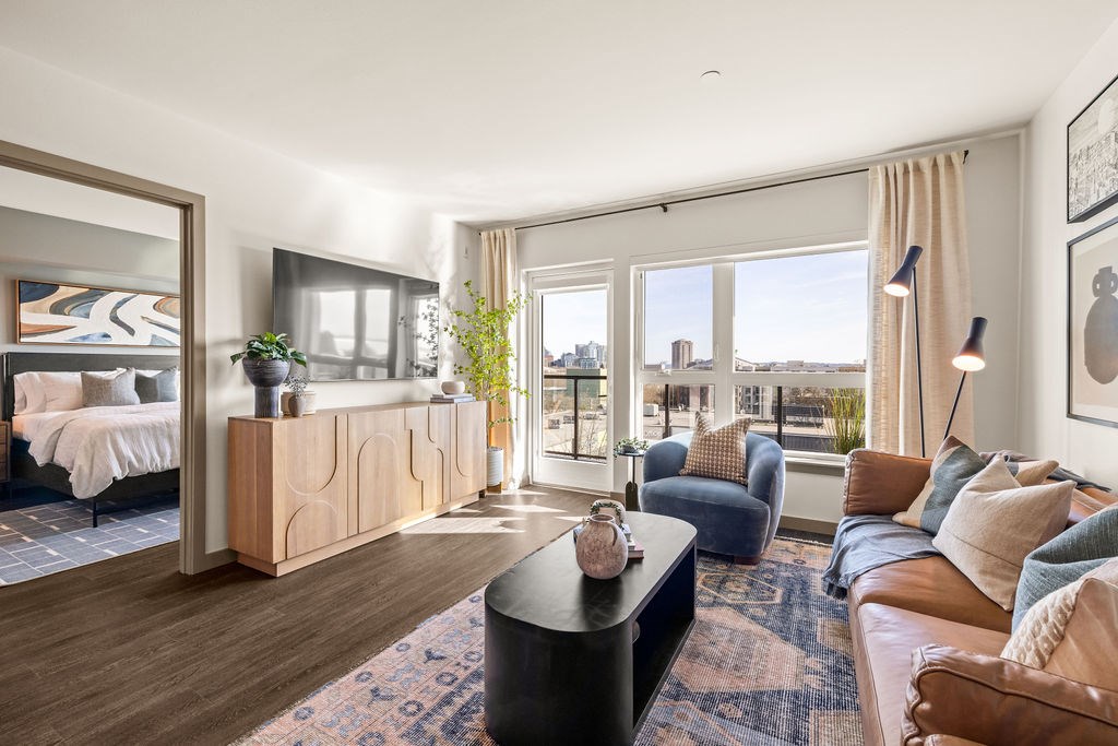 A well-lit, spacious living room with a view of the cityscape outside the windows.