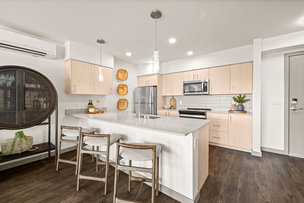 A modern kitchen with a white island and wooden floors.