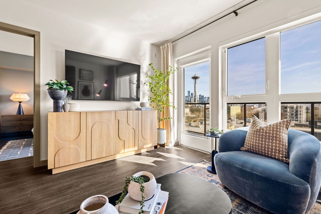 A living room with a blue chair and a flat screen TV mounted on a wooden cabinet.