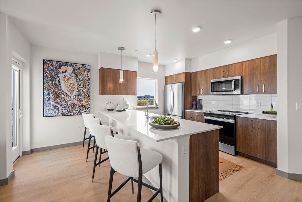 A modern kitchen with a white island and chairs.