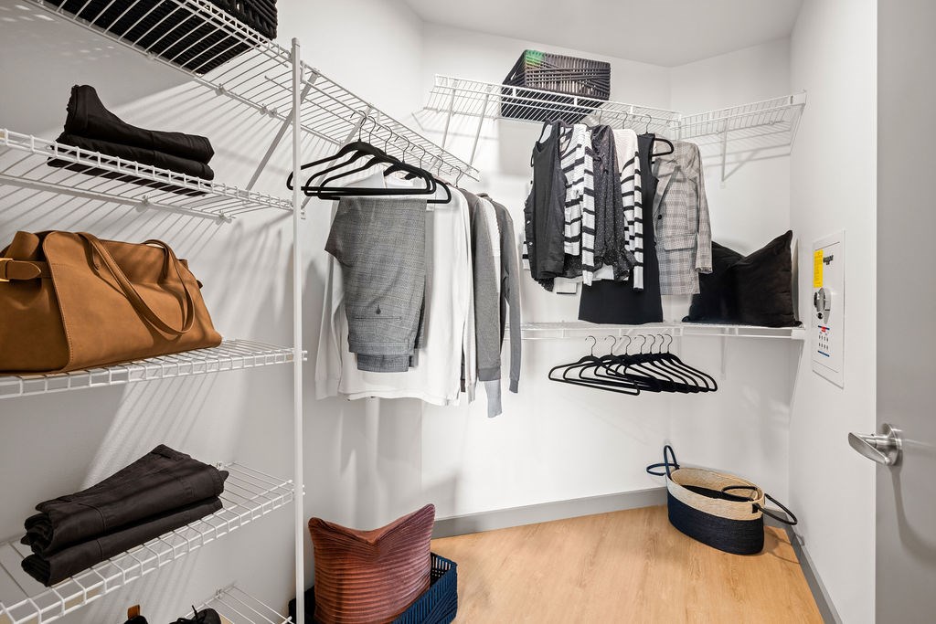 A white closet with clothes hanging and folded on shelves.