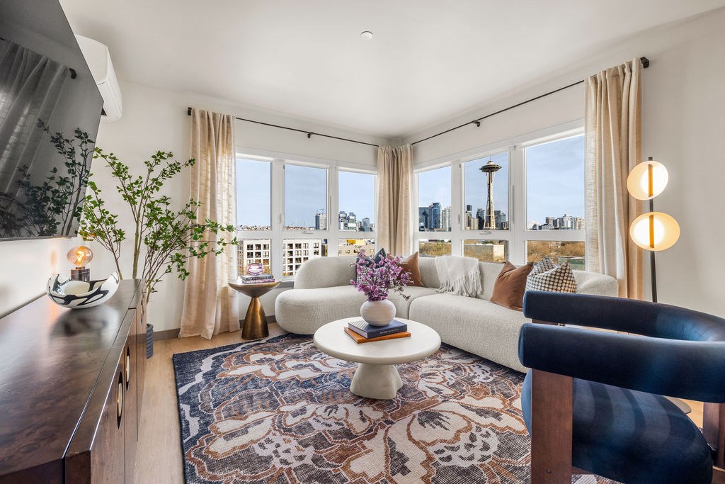 A living room with a couch, a table, and a view of the city.