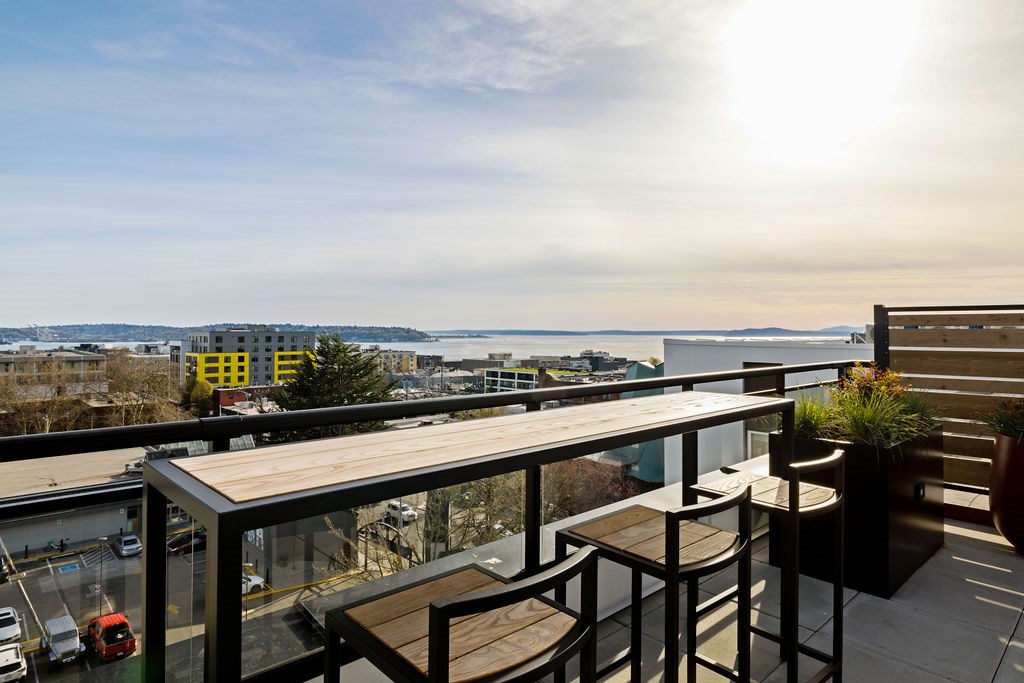 A balcony with a table and chairs overlooking a cityscape.